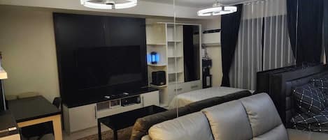 A modern living room with a flat-screen TV, a sofa, a coffee table, and a built-in entertainment unit.