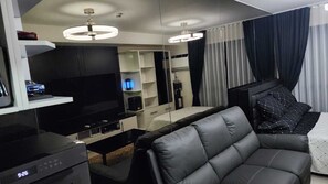 Ein modernes Wohnzimmer mit Flachbildfernseher, einer Couch, einem Couchtisch und einem Bücherregal.