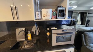 Een kleine keuken met een magnetron, koffiezetapparaat en waterkoker.