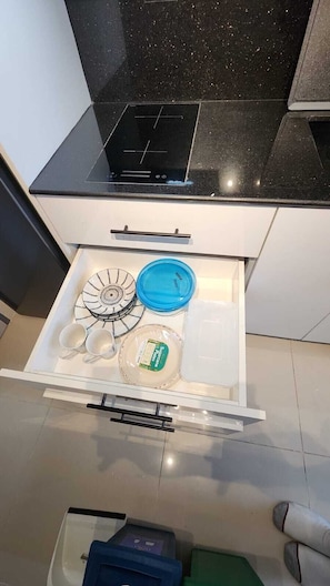Eine Küche mit schwarzer Arbeitsplatte, einer weißen Schublade mit blauem Deckel und einem weißen Teller mit grünem Etikett.