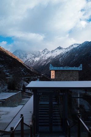 A mountain view with a stone building and a staircase leading to a viewing platform.