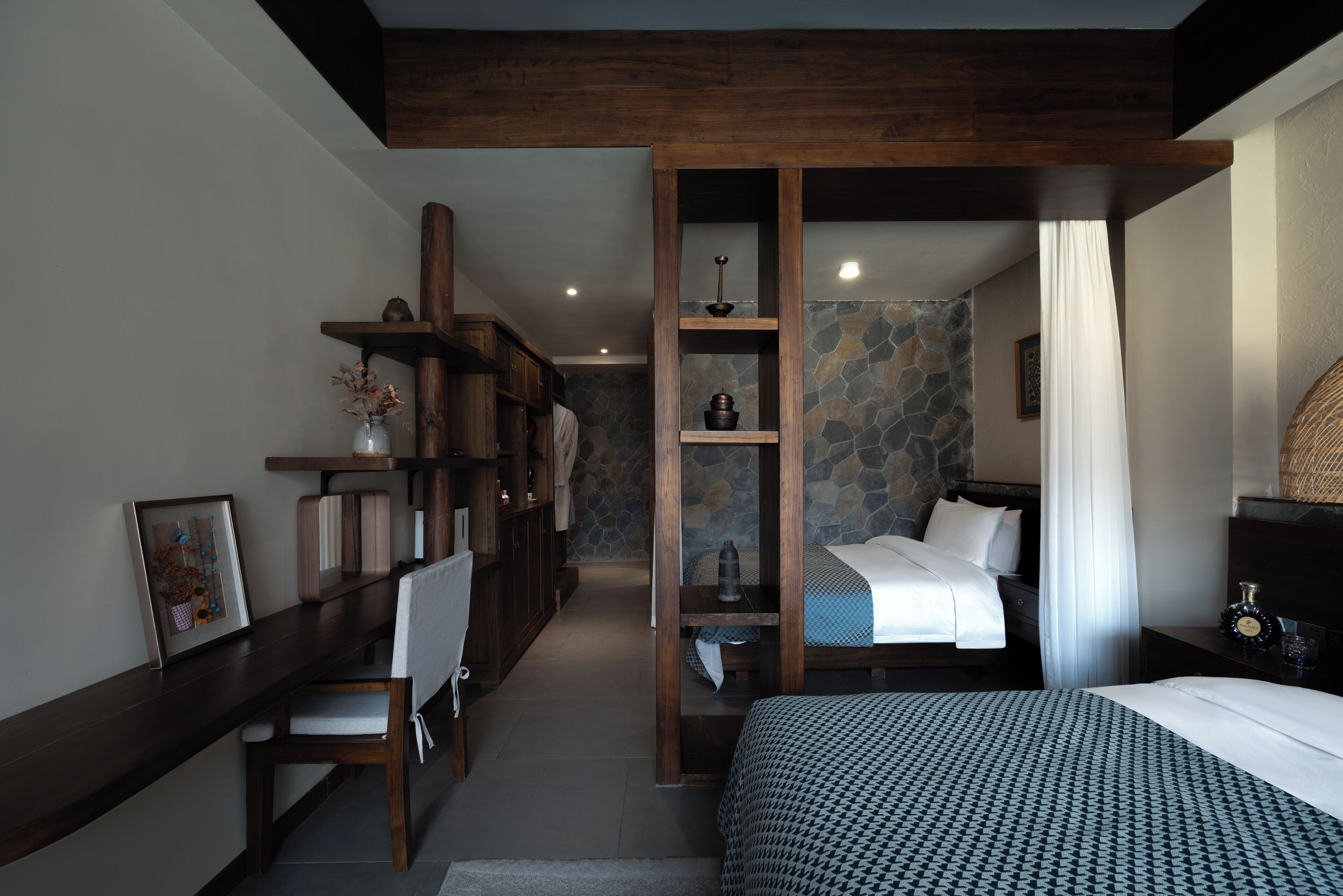 A hotel room with a bed, a desk, a chair, a wardrobe, and a bathroom with a shower.