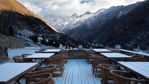 A restaurant with outdoor seating overlooking a mountainous landscape.