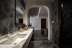 A modern bathroom with a large mirror, a marble sink, and a stone accent wall. - Yueshan Four Seasons Homestay (Ngawa Autonomous Prefecture)