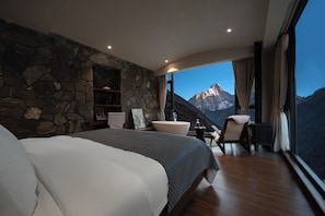 A bedroom with a large bed, a stone wall, a bathroom, and a view of a mountain. - Yueshan Four Seasons Homestay (Ngawa Autonomous Prefecture)