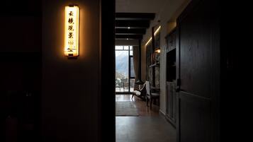 A hallway with a lit sign, a view of mountains through a window, and a stone wall.