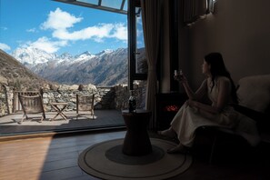 A room with a large window overlooking a mountainous landscape.