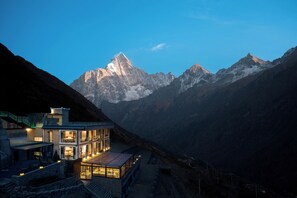 A modern mountain lodge with glass walls, a stone exterior, and a view of snow-capped peaks. - Yueshan Four Seasons Homestay (Ngawa Autonomous Prefecture)
