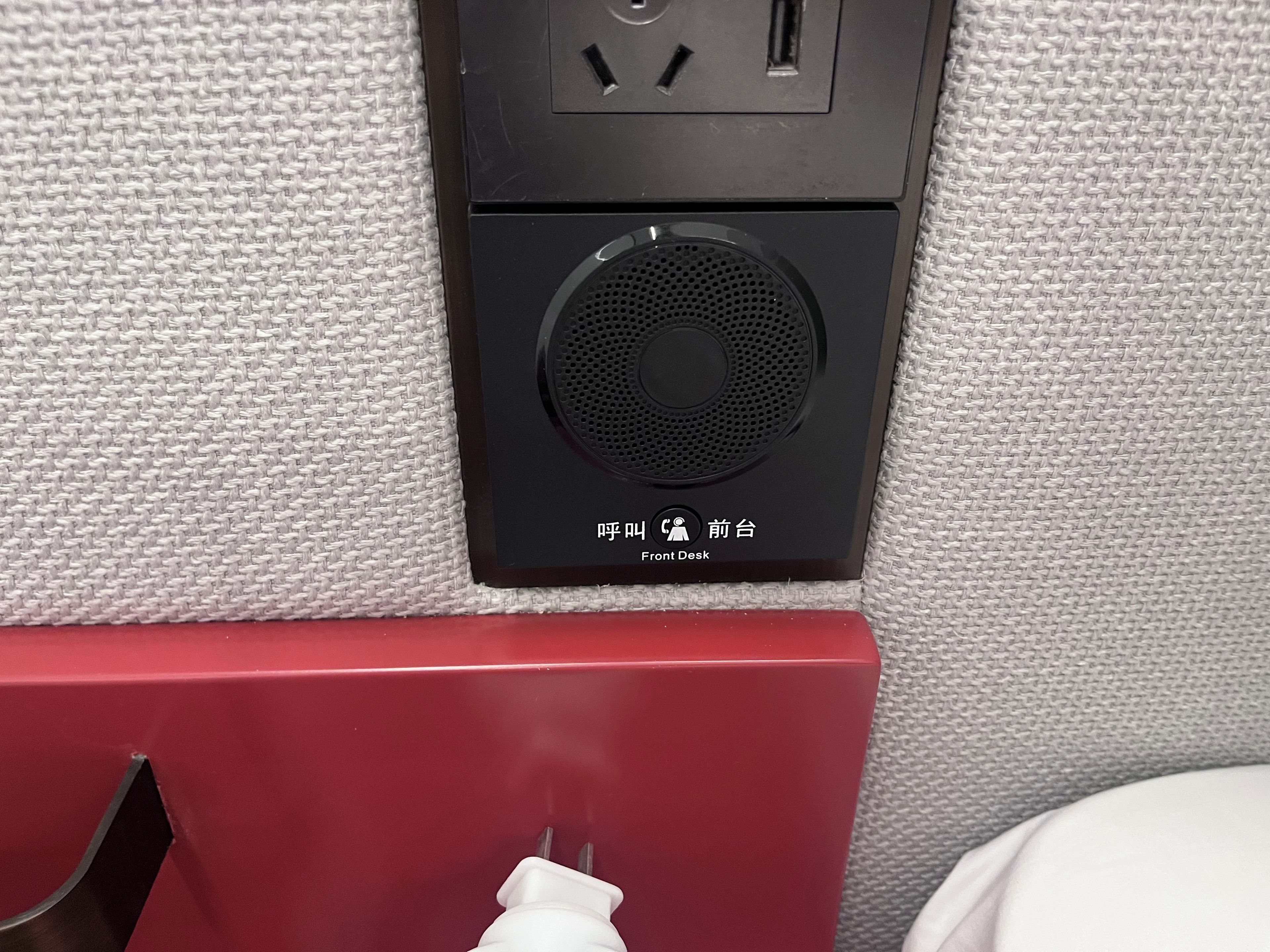 Eine Steckdose mit eingestecktem Stecker, ein Lautsprecher und ein Etikett mit chinesischen Schriftzeichen.