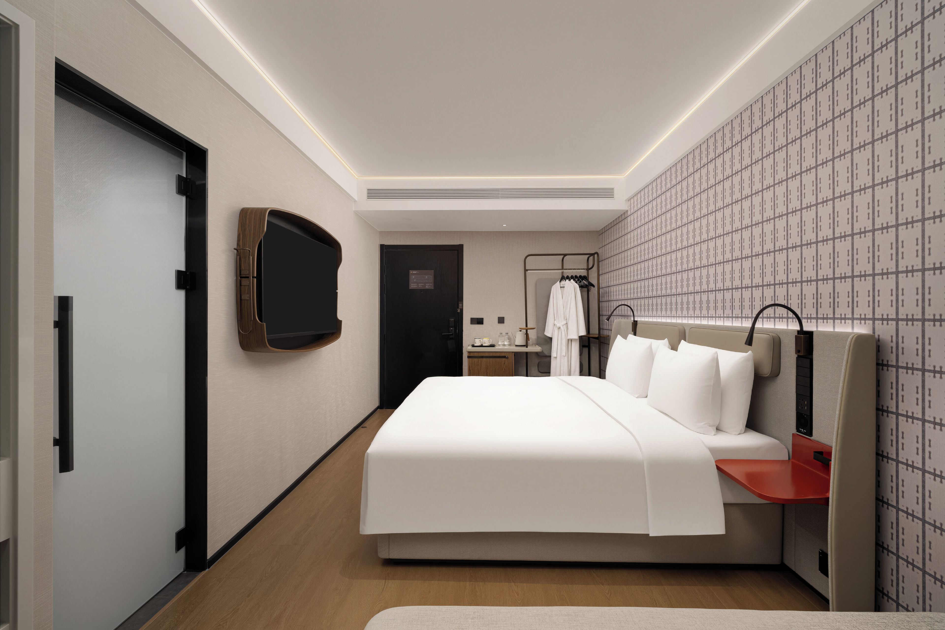 Une chambre d’hôtel avec un grand lit, une table de chevet, une télévision, une armoire et une salle de bain visible à travers une porte ouverte.