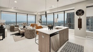 Een moderne keuken met een groot eiland, een zithoek met een bank en stoelen, en uitzicht op de stad door grote ramen.