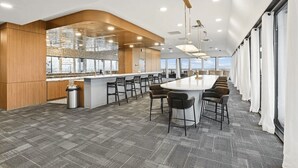 Eine moderne Küche mit Bar, großen Fenstern und hoher Decke.