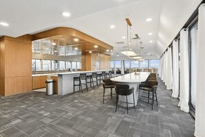 A modern kitchen with a bar area, large windows, and a high ceiling. - Luxury 2BR | King Bed + Space to Gather (Birmingham)
