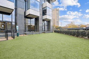 A modern building with a flat roof, large windows, and a grassy courtyard. - Luxury 2BR | King Bed + Space to Gather (Birmingham)