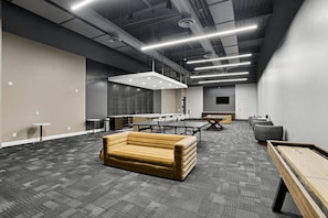 A modern lounge area with a sofa, a pool table, and a long table, featuring a high ceiling with exposed ductwork and recessed lighting. - Luxury 2BR | King Bed + Space to Gather (Birmingham)