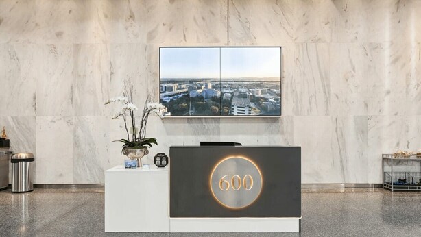 En receptionsdisk med ett stort fönster som vetter ut mot stadsbilden, en krukväxt och en papperskorg.