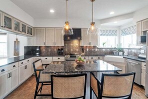 A modern kitchen with a central island, pendant lighting, and a dining area with chairs. - Beautiful Ranch with Hot Tub Near Mt.Princeton Hot Springs (Nathrop)