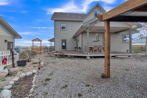 A residential property with a covered patio, a gravel driveway, and a wooden fence. - Beautiful Ranch with Hot Tub Near Mt.Princeton Hot Springs (Nathrop)