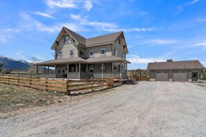 A two-story house with a porch, a garage, and a gravel driveway. - Beautiful Ranch with Hot Tub Near Mt.Princeton Hot Springs (Nathrop)