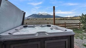 A hot tub with a wooden fence in the background and mountains in the distance. - Beautiful Ranch with Hot Tub Near Mt.Princeton Hot Springs (Nathrop)
