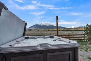 A hot tub with a wooden fence in the background and mountains in the distance. - Beautiful Ranch with Hot Tub Near Mt.Princeton Hot Springs (Nathrop)
