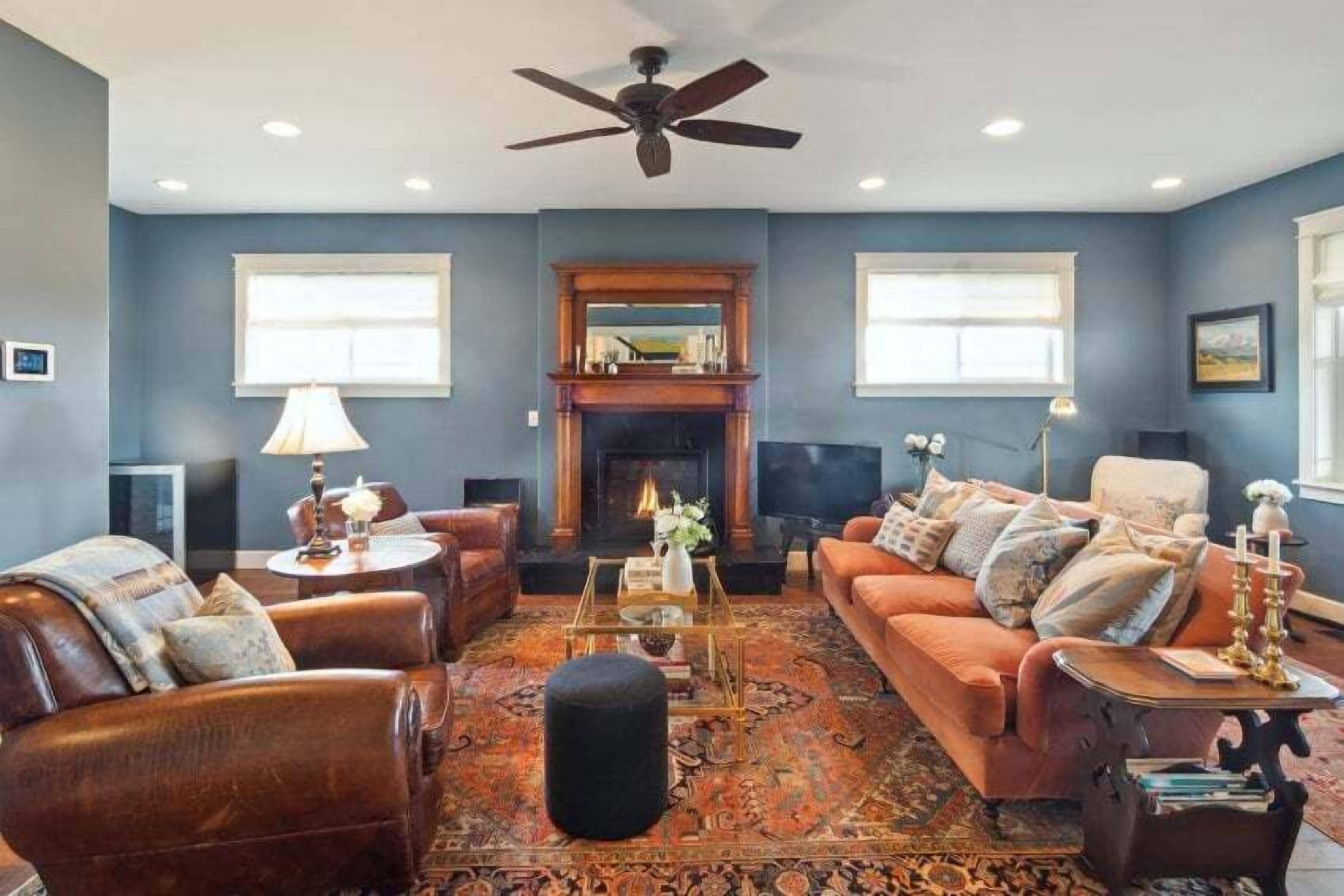 A living room with a fireplace, leather sofas, a coffee table, and a ceiling fan.