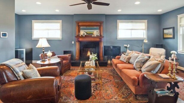 A living room with a fireplace, leather sofas, a coffee table, and a ceiling fan. - Beautiful Ranch with Hot Tub Near Mt.Princeton Hot Springs (Nathrop)