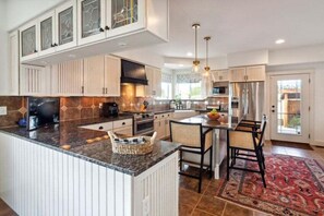 A modern kitchen with white cabinetry, a granite countertop, and a central island with seating. - Beautiful Ranch with Hot Tub Near Mt.Princeton Hot Springs (Nathrop)