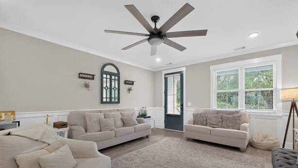 Ein Wohnzimmer mit Deckenventilator, zwei Sofas, einem Couchtisch und einem Fenster mit Jalousien.