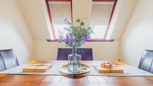 A dining table with a clear glass vase, two wooden boards, and a tray in the center.