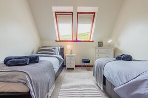 A bedroom with two beds, a nightstand, a dresser, and a window with a view. - Apartment Sleeps 5 with Parking (Lairg)