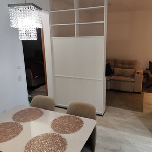 Un comedor con una mesa blanca, sillas color beige y una lámpara de araña.