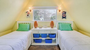 A bedroom with two beds, a window, and a shelf with blue bins. - A-Frame in the Sand - Oceanfront + Pet-Friendly (New Smyrna Beach)