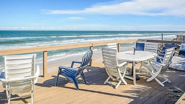 A wooden deck with outdoor furniture overlooking the ocean. - A-Frame in the Sand - Oceanfront + Pet-Friendly (New Smyrna Beach)
