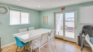 A room with a white table and chairs, a clock, a framed picture, and an exit sign. - A-Frame in the Sand - Oceanfront + Pet-Friendly (New Smyrna Beach)
