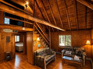A wooden cabin interior with a staircase, a sofa, a table, and a bed. - Lake Harmony retreat with hot tub, sauna, game room, and ski access (Lake Harmony)