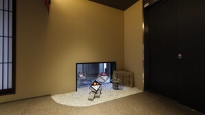 A hallway with a large black door, a small decorative item on the floor, and a wall-mounted light fixture. - Kaleido inn Hiroshima (Hiroshima)