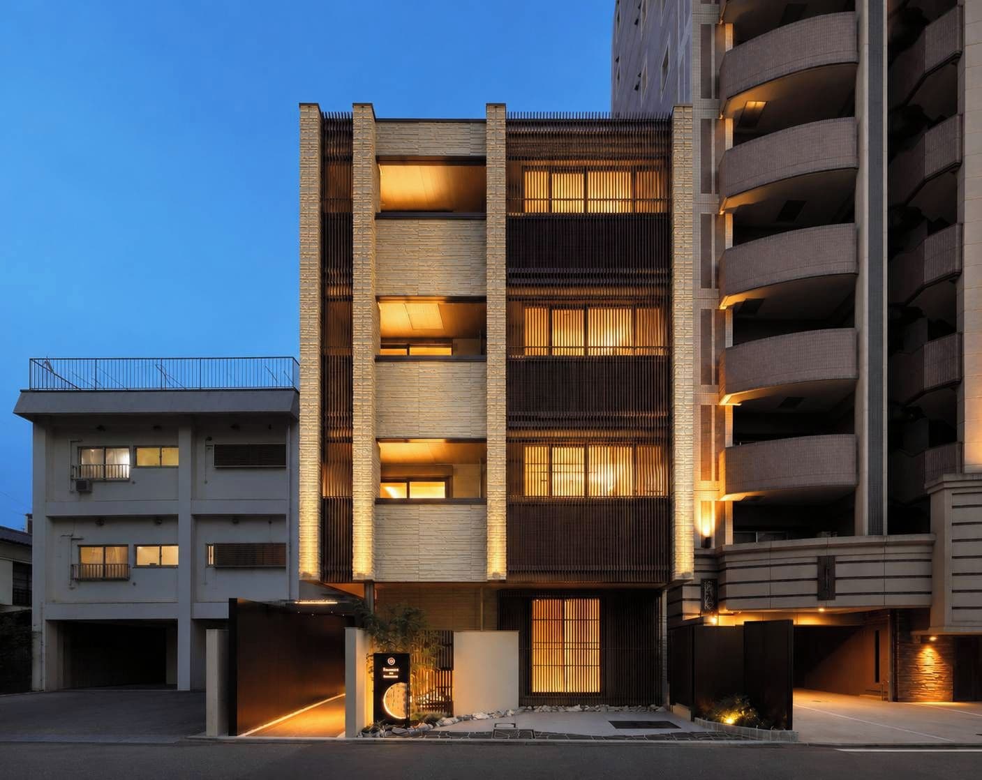 Un edificio a più piani dal design moderno, con balconi e un ingresso carrabile.