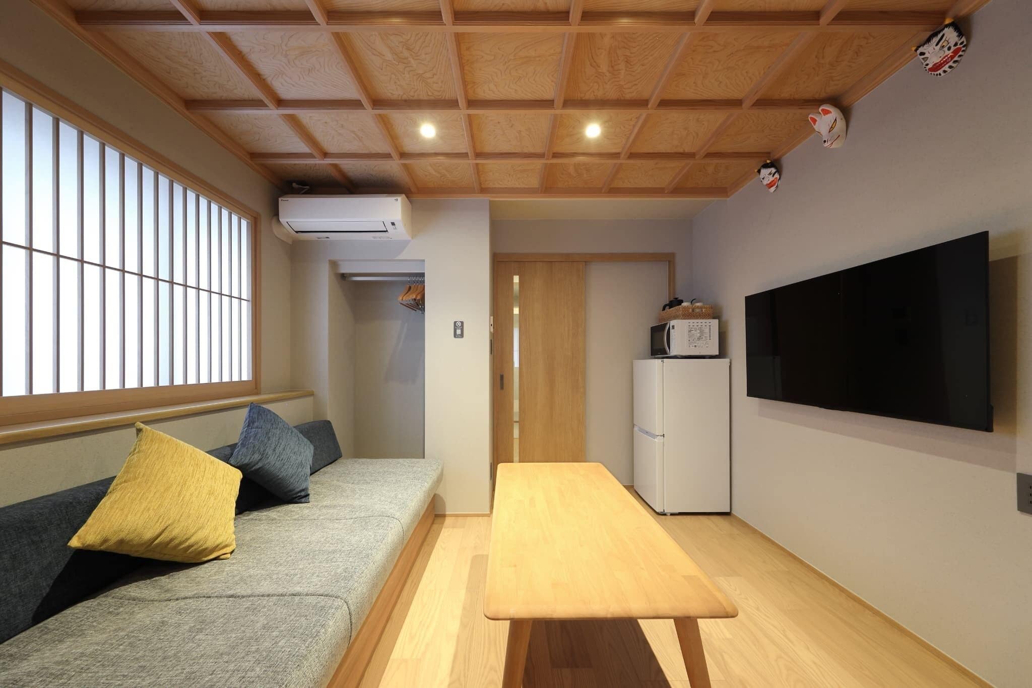 A compact living space with a sofa, a dining table, a TV, and a refrigerator.