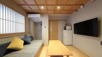 A compact living space with a sofa, a dining table, a TV, and a refrigerator.
