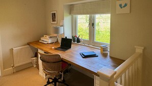 Una oficina en casa con escritorio, silla, laptop y ventana con vista a zonas verdes.