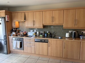 A modern kitchen with wooden cabinets, stainless steel appliances, and a tiled backsplash. - Waterville Village Retreat - Sleeps 6 - Wood Stove (Waterville)