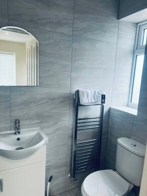 A bathroom with a white sink, a mirror, a towel rack, and a toilet. - Cosy Studio Near Heathrow airport/ Free Parking (Staines-upon-Thames)