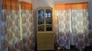 A room with a wooden cabinet, patterned curtains, and a floor lamp. - 1910 Beautiful Craftsman Style Home (Topeka)