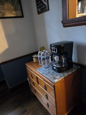 Eine Küchenarbeitsplatte mit einer Kaffeemaschine, einem Schrank und einem gerahmten Bild an der Wand.