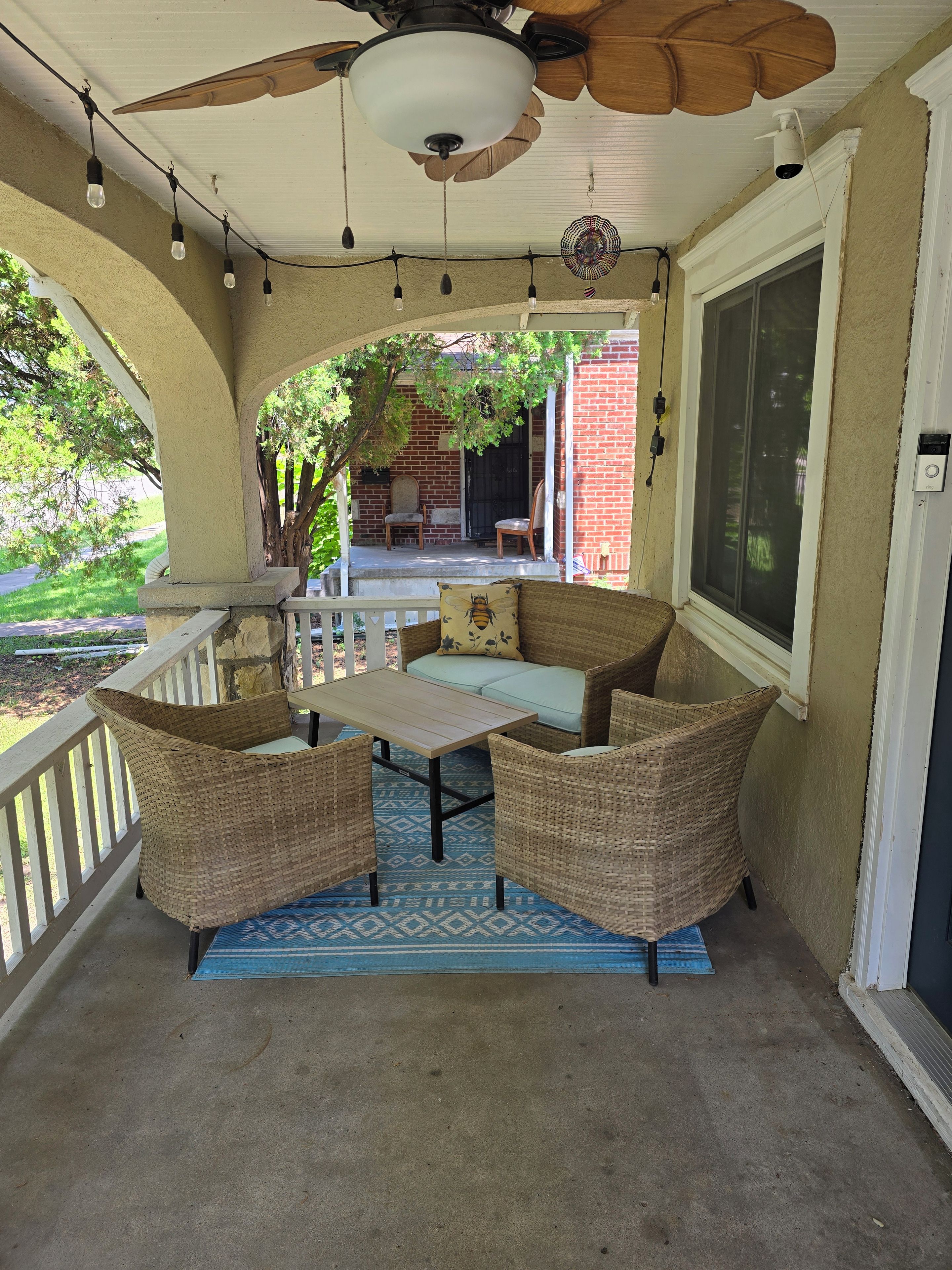 A covered porch with wicker furniture, a ceiling fan, and a view of the backyard.