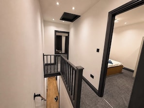 A modern interior with a staircase, a bed, and a small seating area. - Tranquil Haven in Hornchurch - 3 bed house (Hornchurch)
