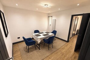 A small, well-lit room with a table and four chairs, a ceiling light, and a door leading to another room. - Tranquil Haven in Hornchurch - 3 bed house (Hornchurch)