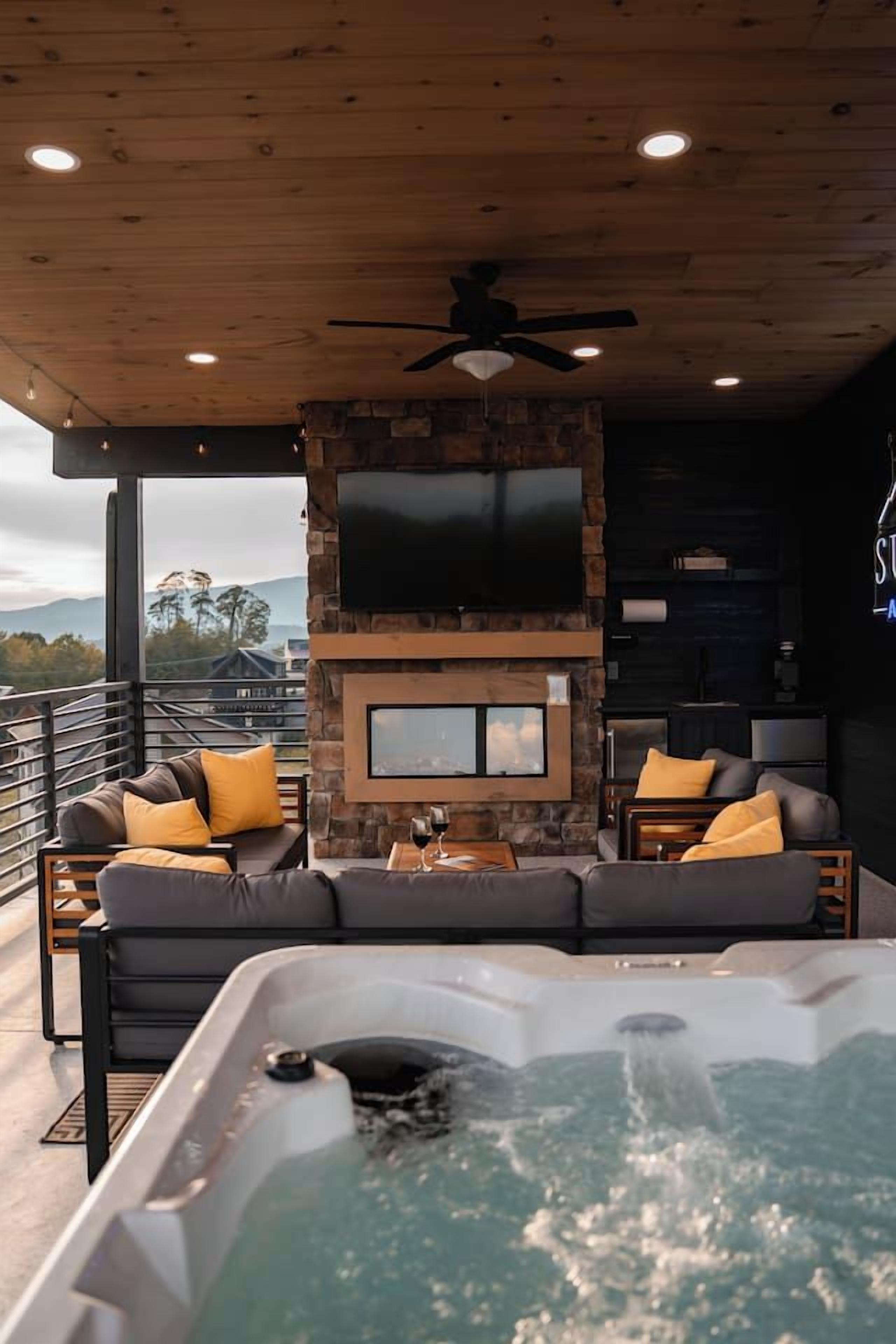 A modern interior with a stone fireplace, a large flat-screen TV, and a hot tub.