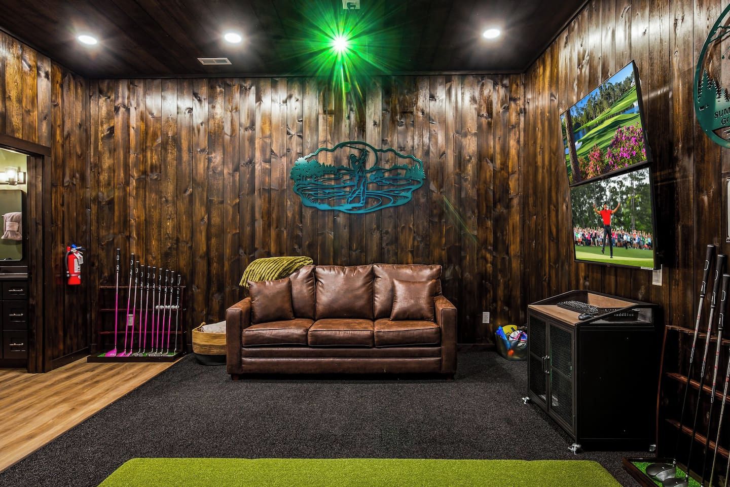 Une pièce avec un mur en bois, un canapé en cuir marron, un téléviseur et une décoration sur le thème du golf.